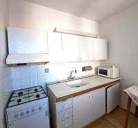 Küche in einer 4-Zimmer-Wohnung mit Herd, weißen Schränken und Mikrowelle.