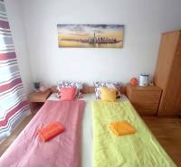 Schlafzimmer in einer Ferienwohnung mit zwei Betten, einem Bild und buntgemusterter Bettwäsche.