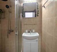 Badezimmer in der Ferienwohnung mit Dusche und Waschbecken, gefliest mit hellen Fliesen.