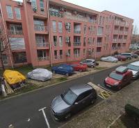 Ferienwohnung in Burgas mit geparkten Autos vor einem rosa Gebäude.