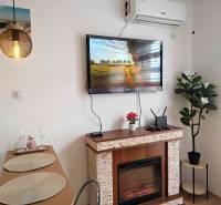 Innenraum einer Ferienwohnung mit Kamin, Fernseher und Esstisch.