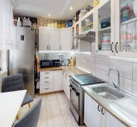 Küche in einer 2-Zimmer-Wohnung mit weißen Schränken und silbernen Geräten.