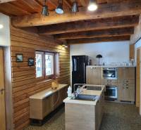 Rustikale Küche in einer Hütte mit Holzdekorationen, hellen Möbeln und Deckenbalken.