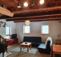 Das Innere der Hütte mit einem Kachelofen, einem Sofa und einer Holzdecke aus massiven Balken.