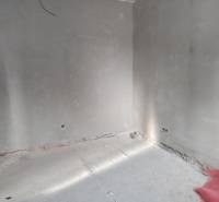 Ein leerer Innenraum mit unverputzten Wänden und Betonboden in einem Einfamilienhaus.