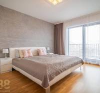 Schlafzimmer in einem Einfamilienhaus mit Bett, Nachttischen und Boden mit Holzdekor.