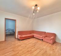 Wohnzimmer in einer 3-Zimmer-Wohnung mit Holzboden und einem orangefarbenen Sofa.