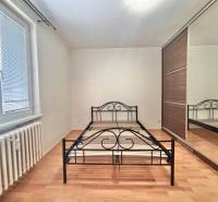 Schlafzimmer mit einem Metallbett, einem Einbauschrank und einem Boden mit Holzdekor in einer 3-Zimmer-Wohnung.