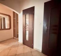 Flur in einer 3-Zimmer-Wohnung mit Fliesen, Spiegel und dunklen Türen.