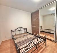 Schlafzimmer in einer 3-Zimmer-Wohnung mit einem Metallbett und einem Schrank, Boden mit Holzdekor.