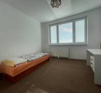 Einfaches Schlafzimmer mit Bett, Schreibtisch und Teppichboden in einer 3-Zimmer-Wohnung.