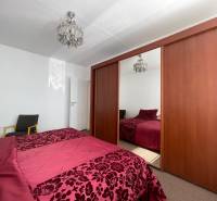 Schlafzimmer mit großem Schrank, Kronleuchter und Bett in einer 3-Zimmer-Wohnung.