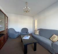 Wohnzimmer in einer 3-Zimmer-Wohnung mit einem bequemen Sofa, Sesseln und einer Vitrine.