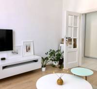 Wohnzimmer in einer 2-Zimmer-Wohnung mit Fernseher, Tisch und Boden in Holzoptik.