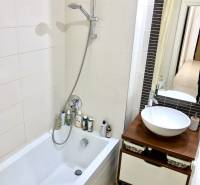 Badezimmer in einer 2-Zimmer-Wohnung mit Badewanne, Dusche und stilvollem Waschtischunterschrank.