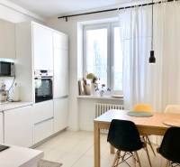 Küche in einer 2-Zimmer-Wohnung mit weißen Schränken und einem Esstisch mit Stühlen.