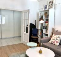 Wohnzimmer mit Holzboden, Sofa und Bücherregal in einer Zweizimmerwohnung.