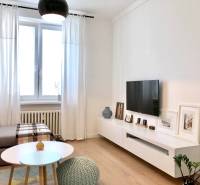 Wohnzimmer in einer Zweizimmerwohnung mit Fernseher, Sofa und Holzboden.