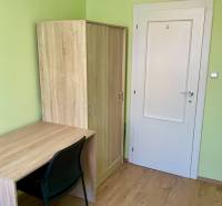 Grünes Zimmer mit Holzmöbeln und Holzboden in einer 3-Zimmer-Wohnung.