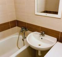 Badezimmer mit Badewanne, Waschbecken und Waschmaschine in einer 3-Zimmer-Wohnung, helle Fliesen.