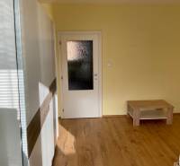 Ein Zimmer mit einem Holzboden, hellen Wänden und einfacher Einrichtung in einer 3-Zimmer-Wohnung.