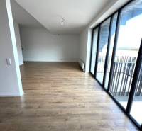 Wohnzimmer in einer Zweizimmerwohnung mit Holzboden und großen Fenstern.