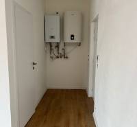 Der Flur in der 2-Zimmer-Wohnung mit einem Boden in Holzoptik und einem Boiler an der Wand.