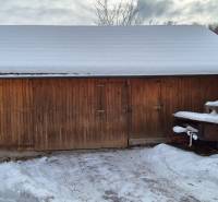 Auf dem Foto aus Ochodnica ist ein hölzerner, zusammenklappbarer Unterstand neben einem Einfamilienhaus mit einer Schneedecke.