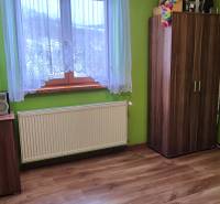Ein Zimmer in einem Einfamilienhaus mit einem Boden in Holzoptik, grünen Wänden und Möbeln.
