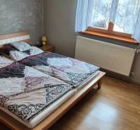 Schlafzimmer im Einfamilienhaus mit Bett, Schrank und Boden in Holzoptik.