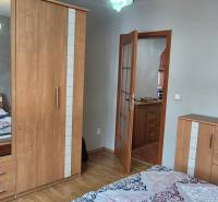 Schlafzimmer im Einfamilienhaus mit Schrank, Holzboden und Zugang zur Küche.
