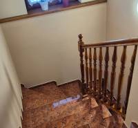Eine Treppe im Einfamilienhaus mit Keramikfliesen und einem Holzgeländer.