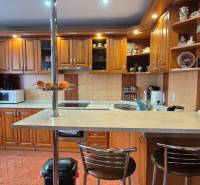 Küche in einem Einfamilienhaus mit Holzschränken, Bartresen und Geräten.