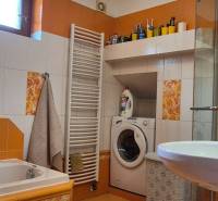 Badezimmer in einem Einfamilienhaus mit Waschmaschine, Duschkabine, Badewanne und bunten Fliesen.