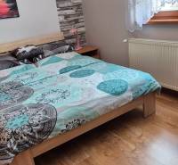 Schlafzimmer im Einfamilienhaus mit Bett, Heizkörper und Boden in Holzoptik.