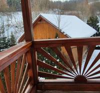 Verschneite Aussicht von einem Holzbalkon eines Einfamilienhauses in Ochodnica in der Straße Ochodnica.