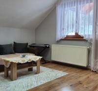 Wohnzimmer in einem Einfamilienhaus mit Sofa, Tisch, Teppich und Holzboden.