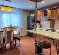 Küche mit Esstisch in einem Einfamilienhaus, Holzschränke und Fliesenboden.