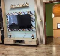 Wohnzimmer in einem Einfamilienhaus mit Holzdekorboden und einem großen Fernseher an der Wand.