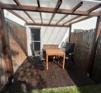 Gartenterrasse mit Holztisch und Stühlen ist mit einer Pergola überdacht.