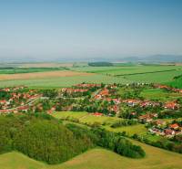 Luftaufnahme von Nemčiňany, umgeben von landwirtschaftlichen und forstwirtschaftlichen Flächen in einer grünen Landschaft.