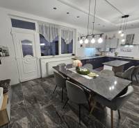 Essbereich mit Steintisch, grauen Stühlen und Hängelampen in einem Einfamilienhaus.