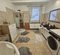 Badezimmer in einem Einfamilienhaus mit Badewanne, Dusche und Waschmaschine.