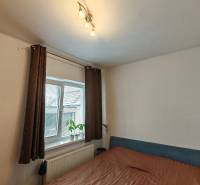 Schlafzimmer im Einfamilienhaus, mit Bett, Regalen und Fenster mit dekorativer Pflanze.