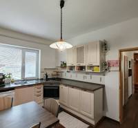 Küche im Einfamilienhaus mit Licht, Spüle, Geschirrspüler und Tisch, Boden mit Holzdekor.