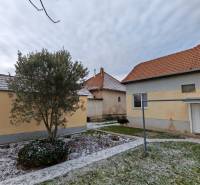 Ein verschneiter Garten mit einem Einfamilienhaus in Trnovec nad Váhom, umgeben von Bäumen und Rasen.