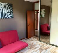 Ein Zimmer mit einem rosa Sofa, einem Bild von einem Zebra und einem Spiegelschrank, einem Boden mit Holzdekor.