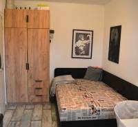 Ein Zimmer in einer 3-Zimmer-Wohnung mit einem Bett, einem Schrank und einem Boden in Holzoptik.