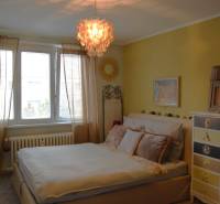 Gemütliches Schlafzimmer mit Vorhängen und Bücherregal in einer 3-Zimmer-Wohnung, die Atmosphäre wird durch einen interessanten Kronleuchter ergänzt.