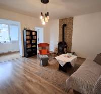 Ein Zimmer in einem Einfamilienhaus mit einem Kaminofen, einem Sofa, einem Bücherregal und einem Boden mit Holzdekor.